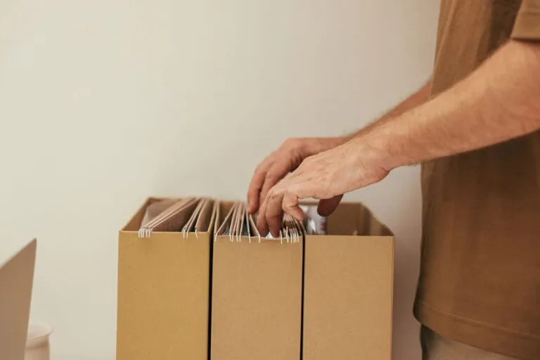 Recurso administrativo no INSS: como contestar o indeferimento sem ir ao Judiciário 2 Close-up of a person organizing files in cardboard boxes, ideal for business and office themes.