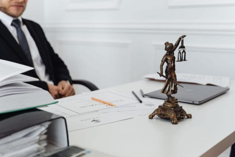 Recurso Contra Indeferimento de Auxílio-Doença 2026: Prazos e Como Reverter 4 A legal professionals workspace featuring Lady Justice statue, documents, and a laptop.