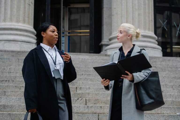 Smart young multiracial female lawyers talking about case standing near aged court buildin