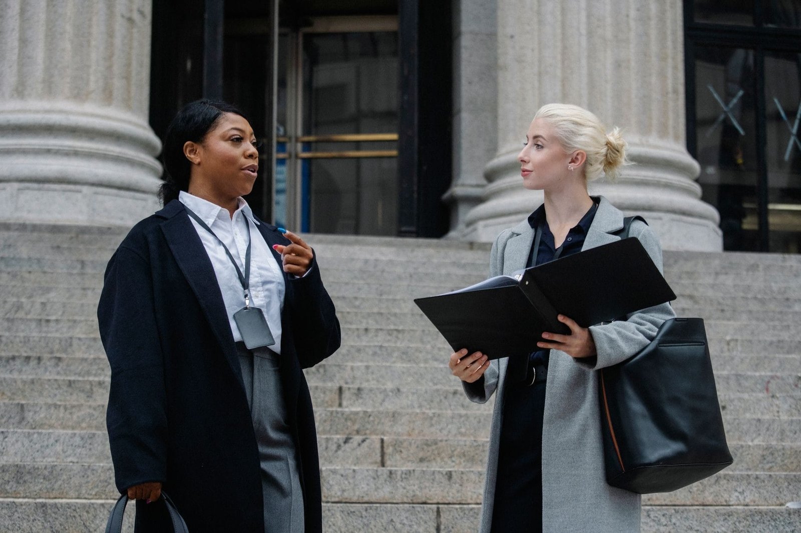 Smart young multiracial female lawyers talking about case standing near aged court buildin