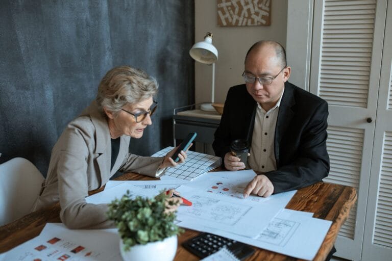 Diverse team of professionals working on project plans at a desk. Collaborative business environment.