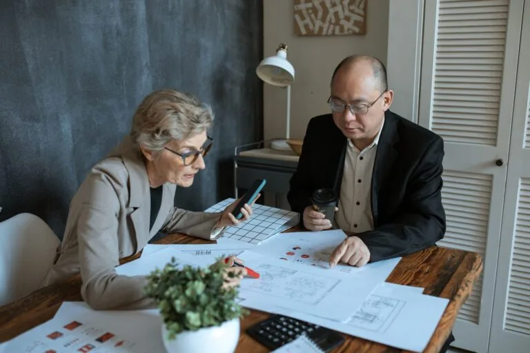 Diverse team of professionals working on project plans at a desk. Collaborative business environment.