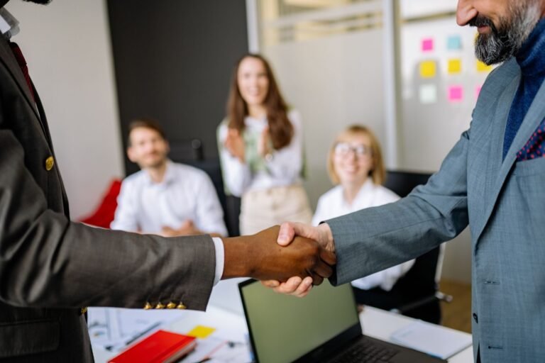 Close-up of a handshake between colleagues in a professional office setting, emphasizing t