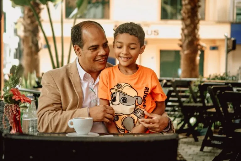 Responsabilidade dos pais por atos dos filhos menores 6 Heartwarming moment of a father and son sharing a coffee at an outdoor café, full of joy.
