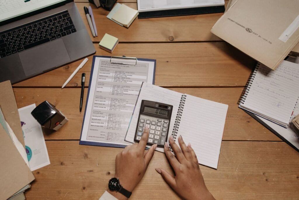 Acho que meu benefício foi calculado errado. Posso pedir revisão? 1 Hands working with calculator and documents on wooden desk in office setting.