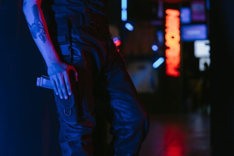 A person in leather pants holding a weapon in a neon-lit setting.