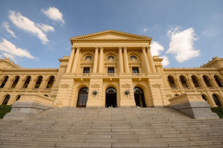 STF declara constitucional a aplicação do fator previdenciário a benefícios sob a regra de transição da EC 20/98 (Tema 616) 7 Stunning view of a neoclassical building with grand columns and stairs under a blue sky.
