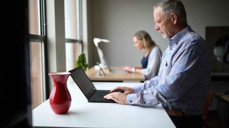 man in blue and white plaid dress shirt using macbook pro