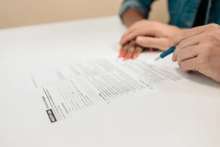 Close-up of hands signing adoption papers in an office environment, symbolizing family and
