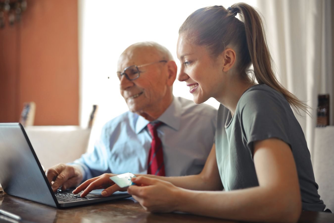STJ fixa critérios de interesse de agir e de data de início do benefício (DIB) em ação previdenciária (Tema 1.124) — acórdão publicado em novembro de 2025 1 Young woman in casual clothes helping senior man in formal shirt with paying credit card in Internet using laptop while