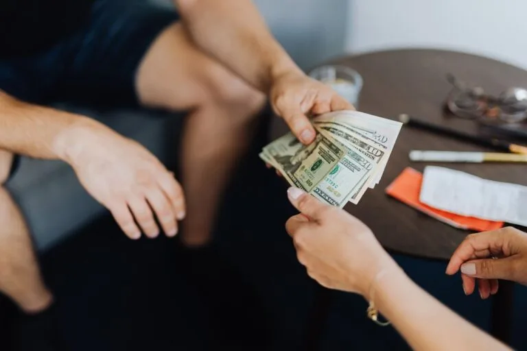 STJ fixa em recurso repetitivo (Tema 1.124) que, quando a prova do direito surge apenas em juízo, os efeitos financeiros do benefício retroagem à data da citação, e não à DER 3 Close-up of hands exchanging US dollar bills, symbolizing a financial transaction or payment.