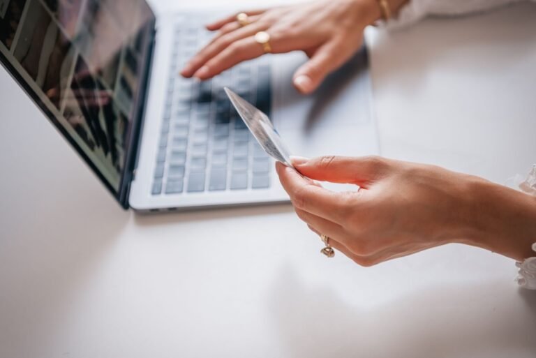 Superendividamento: como renegociar dividas e preservar o minimo para viver 4 Close-up of woman holding a credit card while typing on a laptop, representing online shop