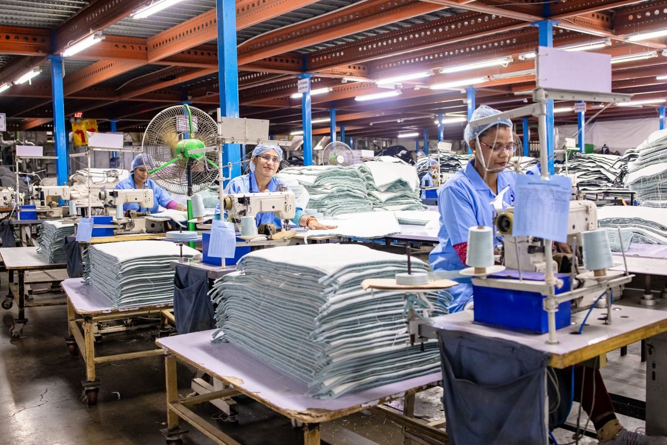 Workers in a textile factory operating sewing machines and organizing fabric.