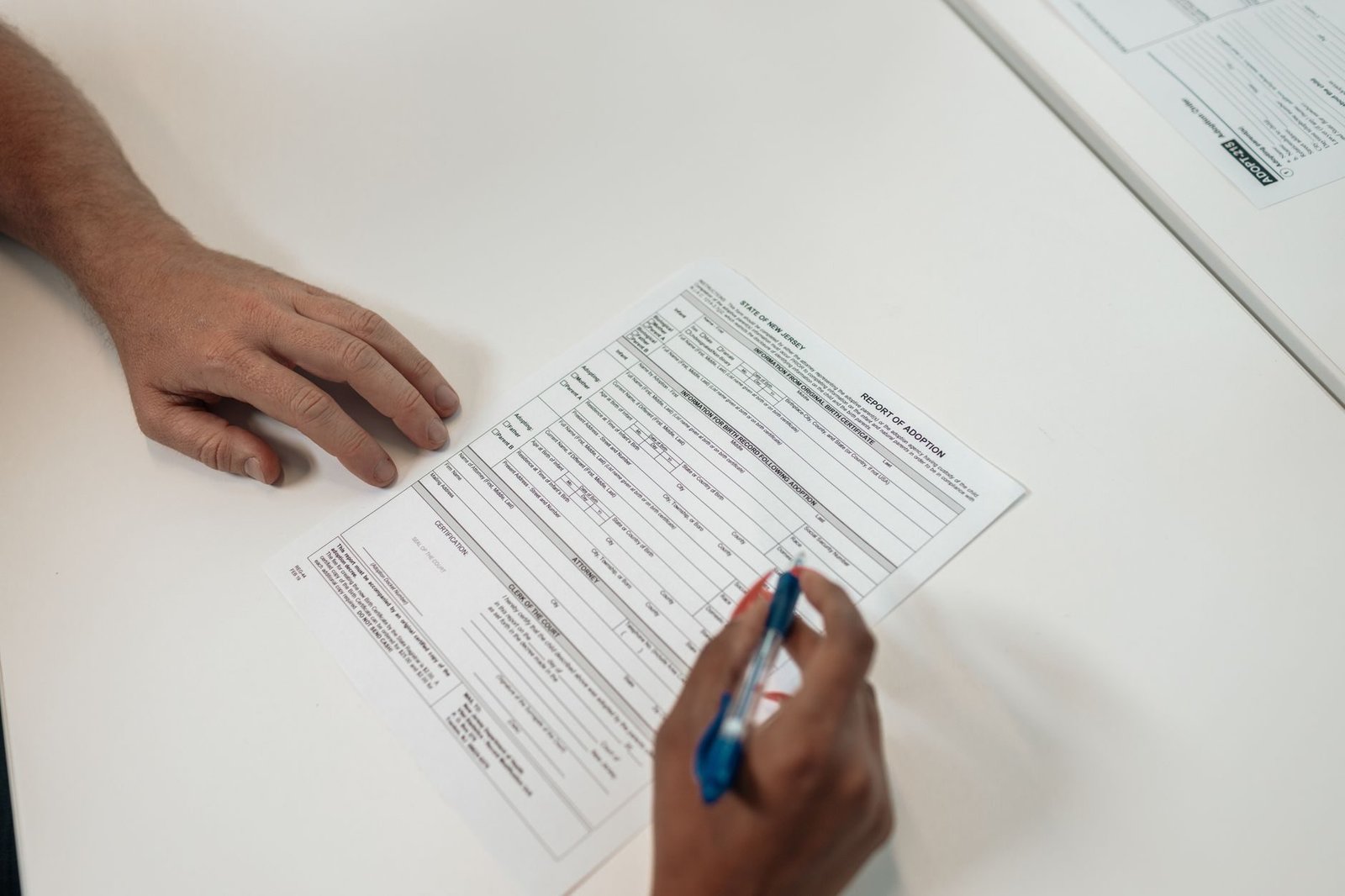 Two people reviewing and signing adoption documents, symbolizing legal procedures and fami