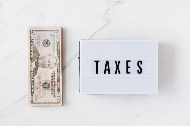 Transacao tributaria: como negociar dividas com a Fazenda e obter descontos 4 Top view composition of stack of American dollars placed on white marble surface with white retro light box with TAXES i