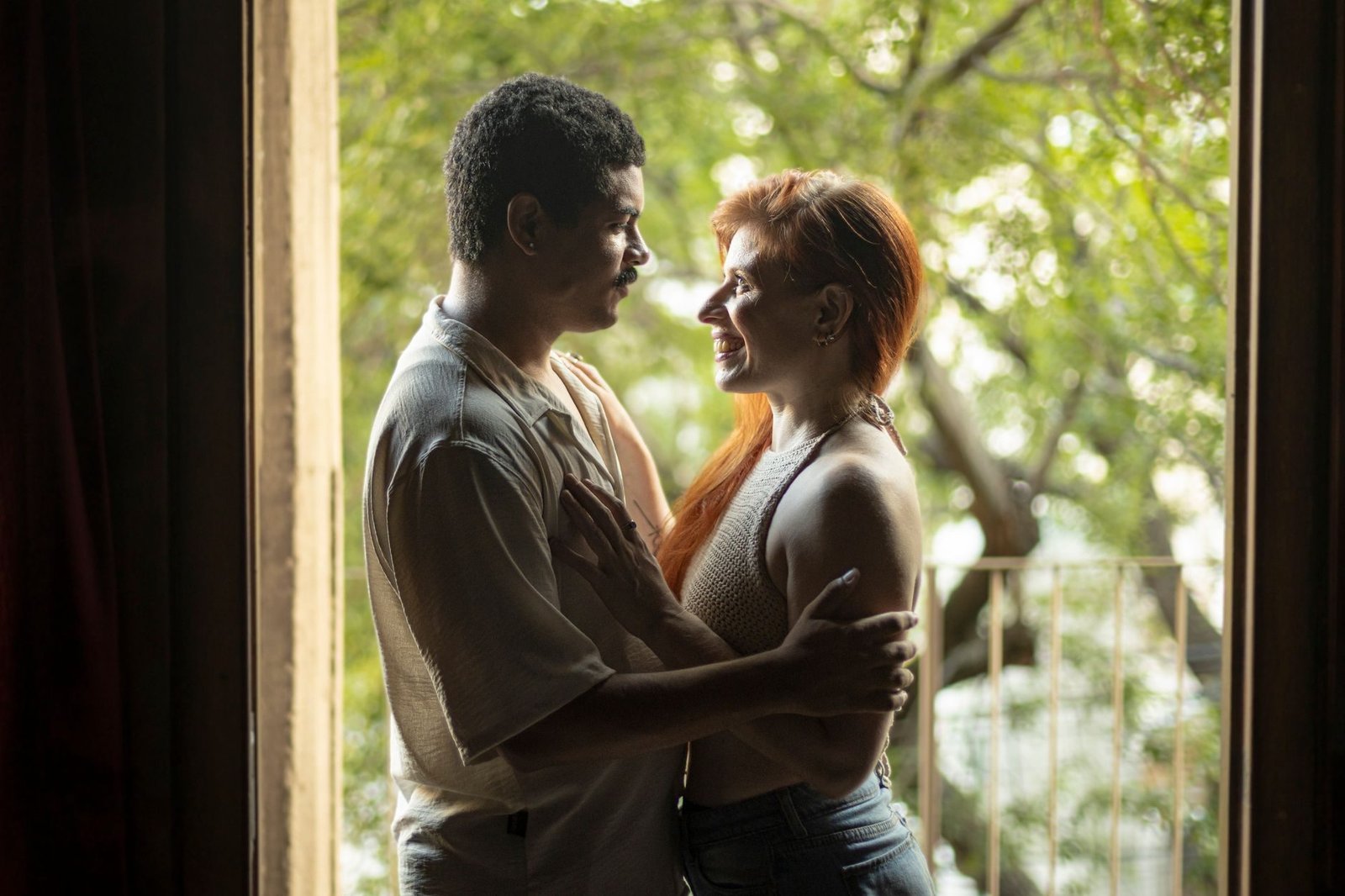 A loving couple sharing a tender moment by a doorway with natural light flowing in. Captur