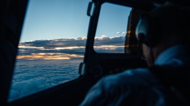 Scenic sunset view from an airplane cockpit flying over the clouds.