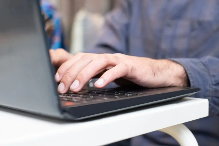 Close-up of hands typing on a laptop keyboard, focused and professional setting.