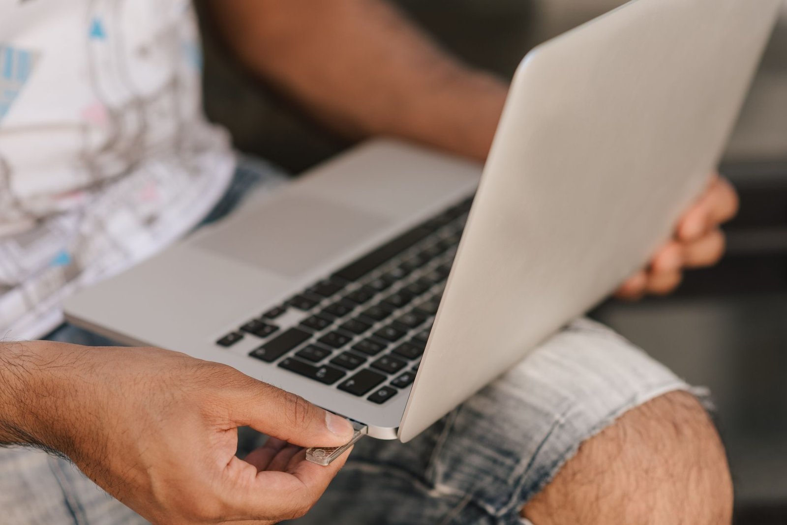 Crop unrecognizable male in casual shorts working on modern netbook placed on laps and ins