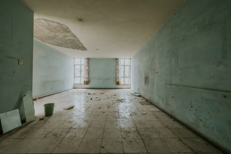 Explore an abandoned room with peeling paint and debris, showing decay.