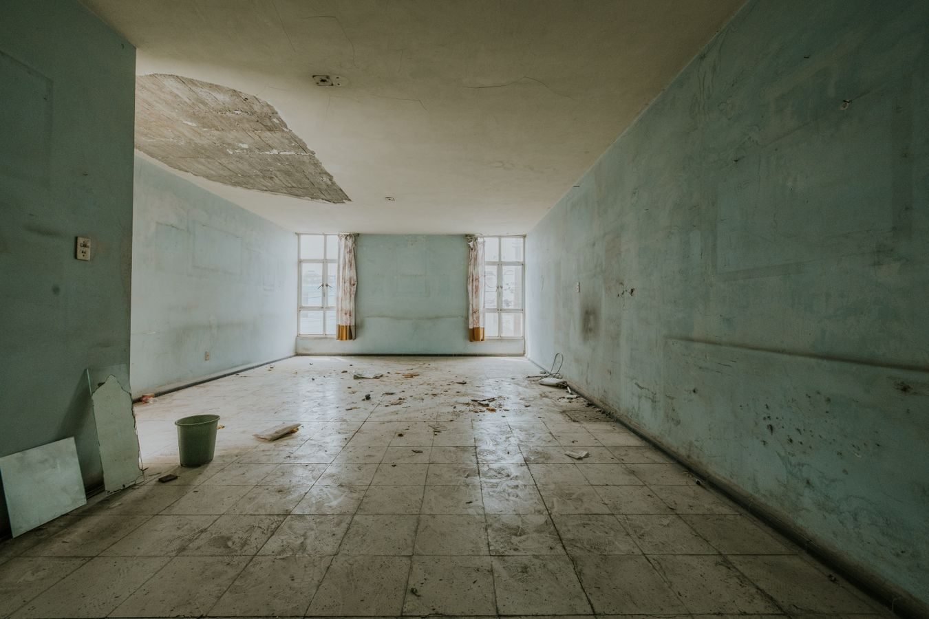 Explore an abandoned room with peeling paint and debris, showing decay.