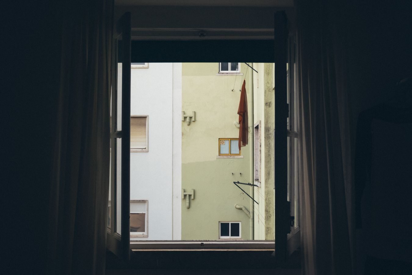 A view of an urban apartment building facade framed by an open window.