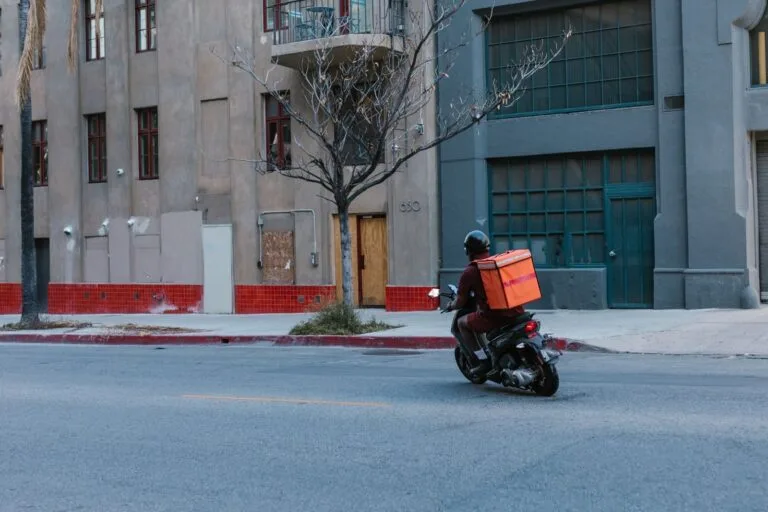 Street view of a courier on a motorcycle delivering in an urban setting.
