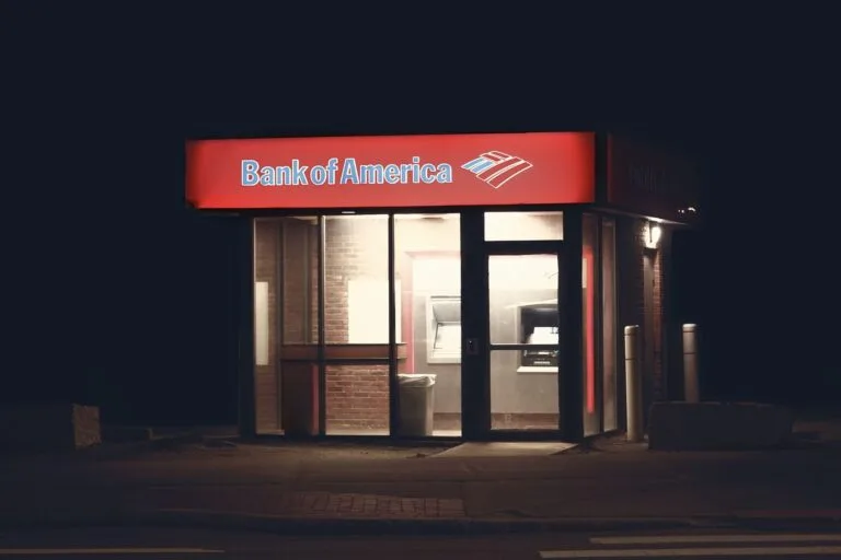 Afastamento do bancário e a contagem do tempo de contribuição 6 Illuminated Bank of America ATM structure against a dark nighttime backdrop in Boston.
