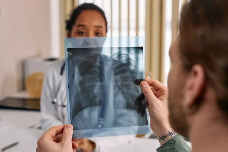 Como Agendar Perícia Médica no INSS: Passo a Passo em 2026 7 Doctor reviews chest x-ray results with patient in a medical office.
