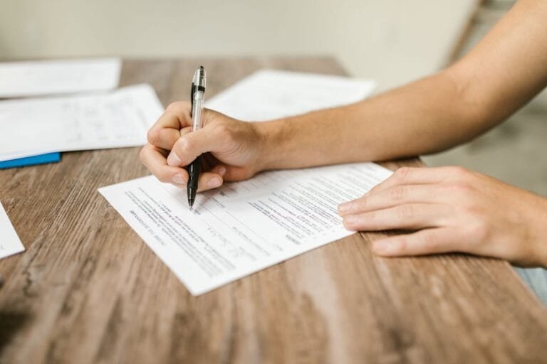 Alienação parental: como identificar e proteger o vínculo com os filhos 6 Hand filling out paperwork with a pen, showcasing focus on document completion.