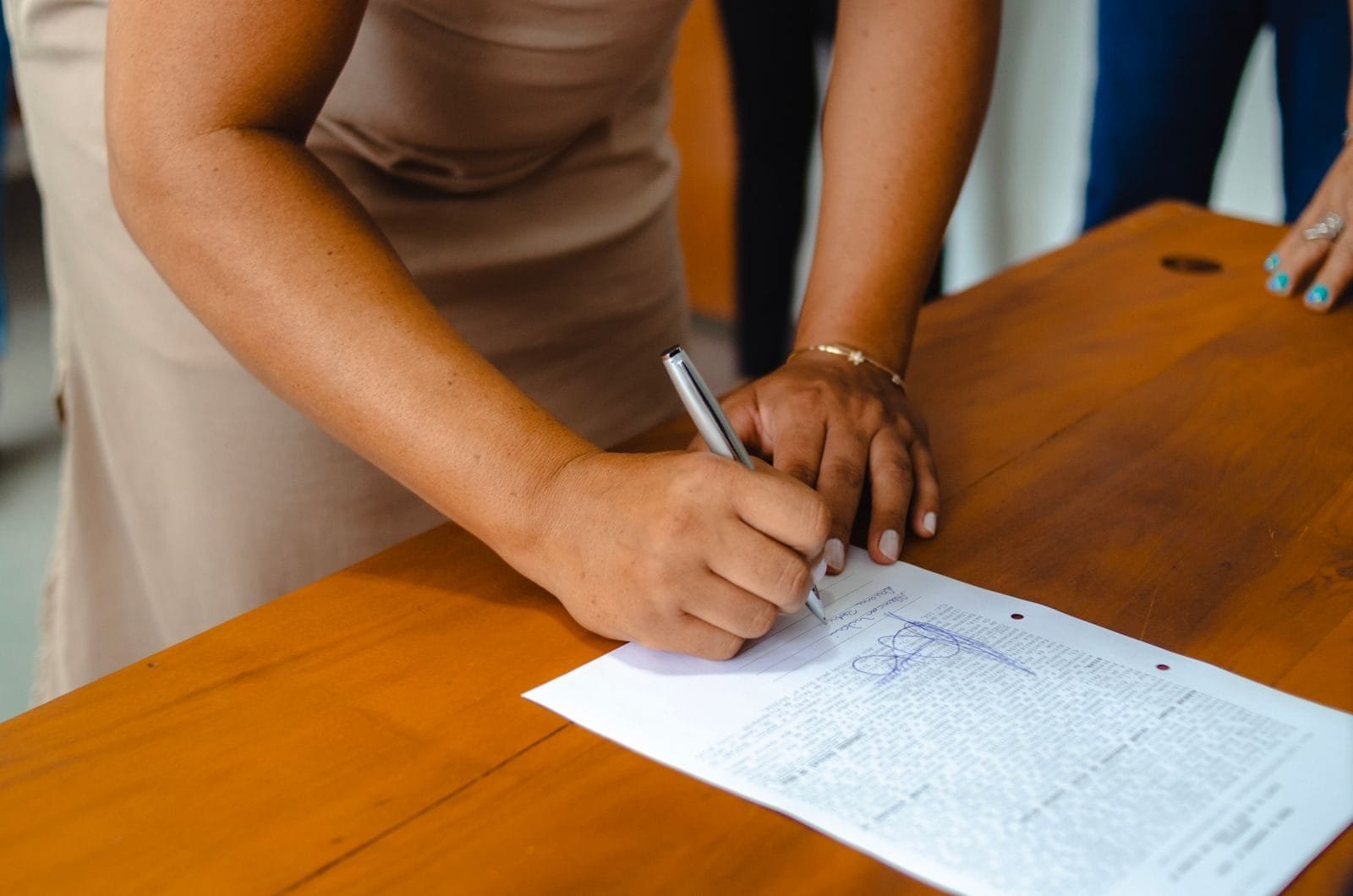 Alterações no contrato administrativo: até onde a administração pode mudar 1 A professional woman signing an official document on a wooden table indoors.