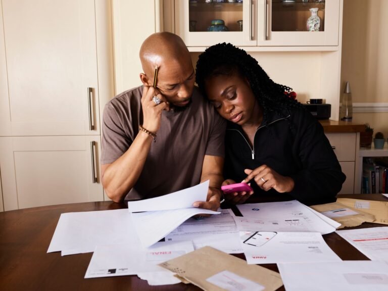 A couple sits at a table managing domestic finances, evaluating documents and using a smar