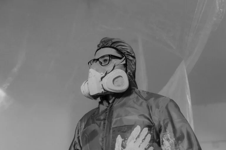 Aposentadoria especial: atividade de risco e exposição a agentes nocivos 4 Worker wearing a gas mask and safety gear in a monochrome setting, emphasizing protection and safety.