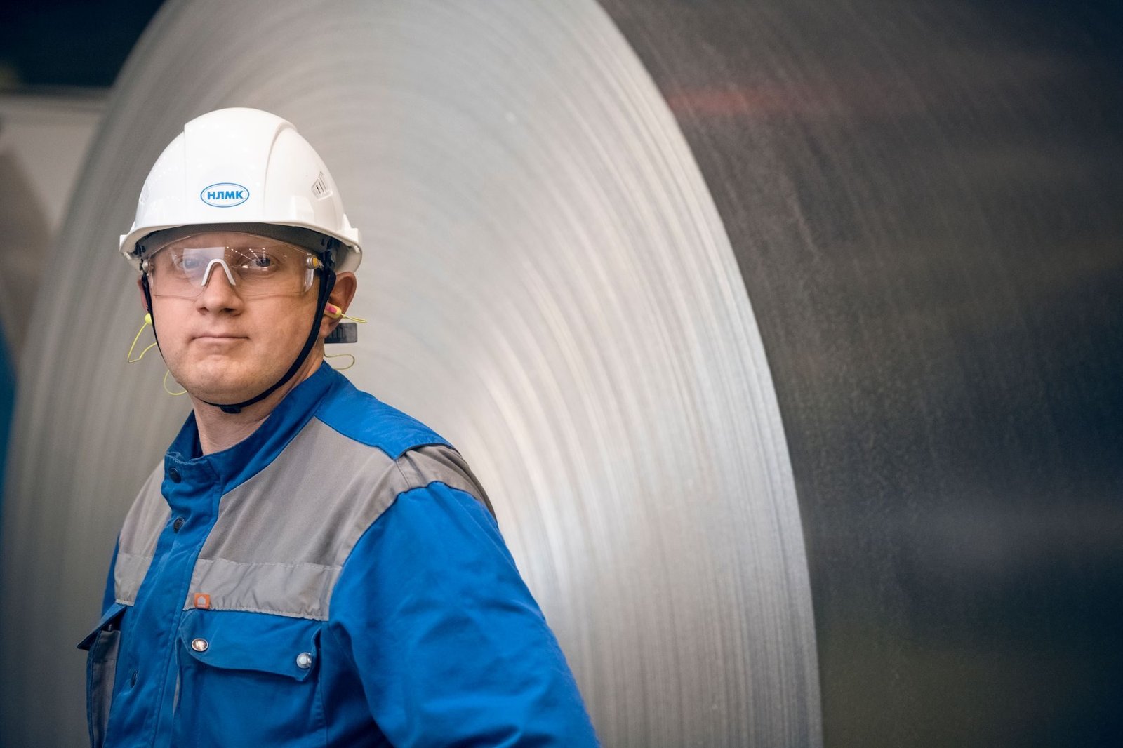 Aposentadoria especial: requisitos para quem trabalhou exposto a agentes nocivos 1 Portrait of a factory worker in protective gear in front of a large steel coil in an indus