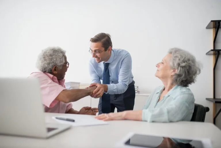 Business professional meeting with senior clients in an office setting, showcasing diversity and cooperation.