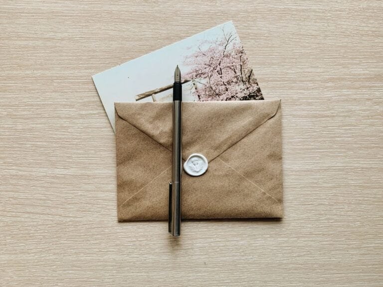 Resultados 1 A classic brown envelope with a wax seal and pen atop a wooden desk, evoking a vintage feel.