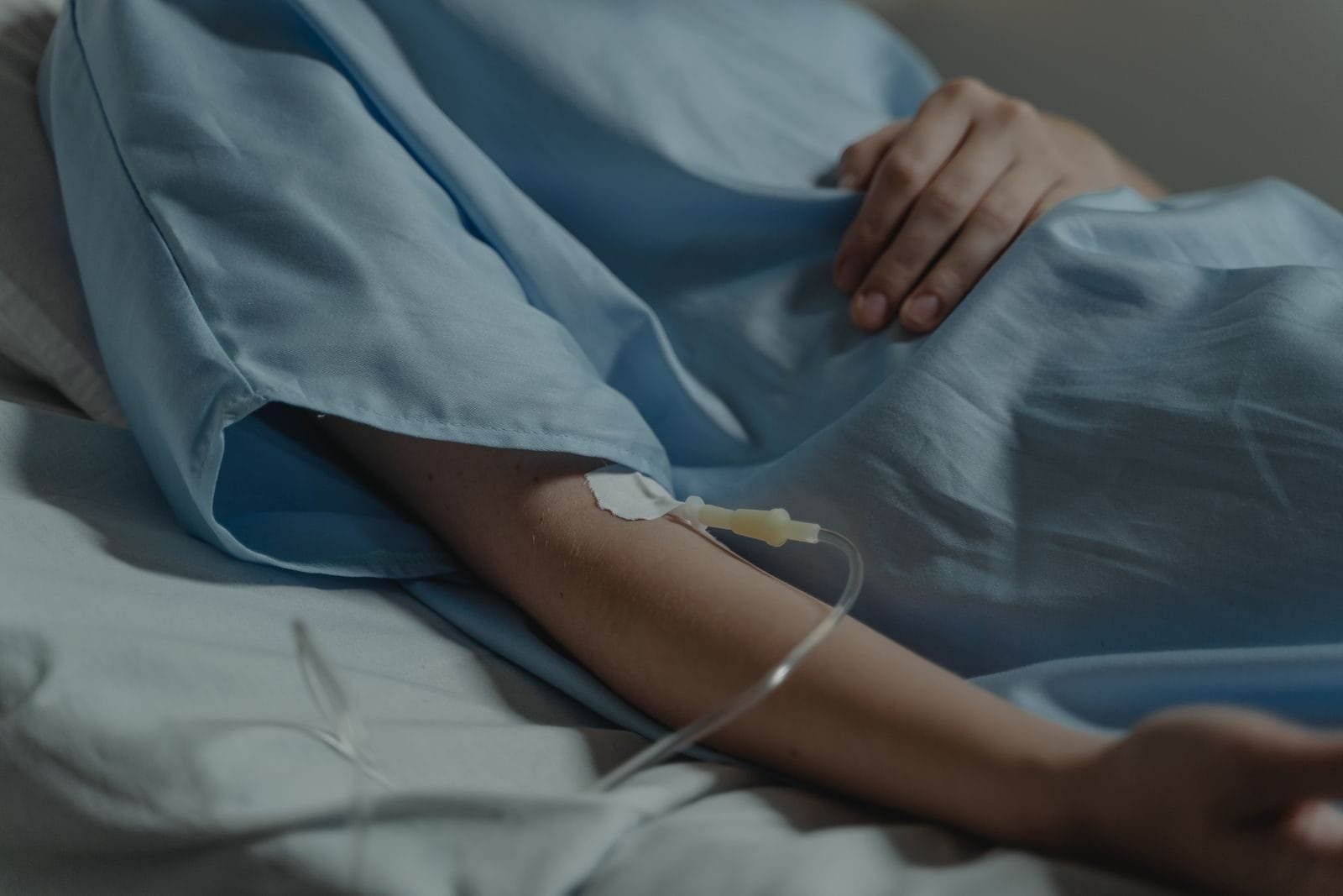 Auxílio por Incapacidade Temporária (Auxílio-Doença): Requisitos e Carência 1 Close-up of a patient in a hospital bed with an IV drip attached to the arm.