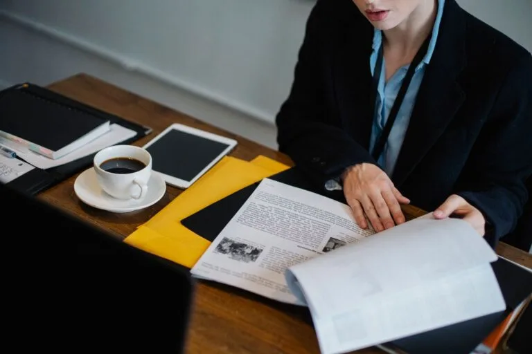High angle of crop faceless businesswoman in formal clothes sitting at table with tablet a