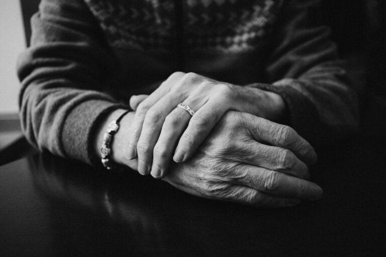 Black and white photograph showcasing elderly hands wearing a wedding ring, conveying warm