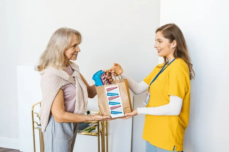Smiling women exchanging a gift bag indoors, showcasing friendship and community support.