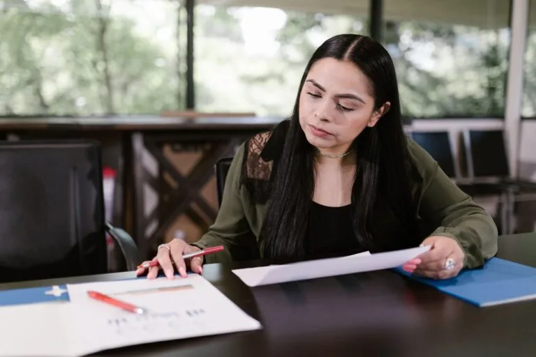 Professional woman in office setting studying documents with concentration.
