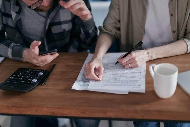 A couple collaboratively managing finances with papers and calculator in hand.