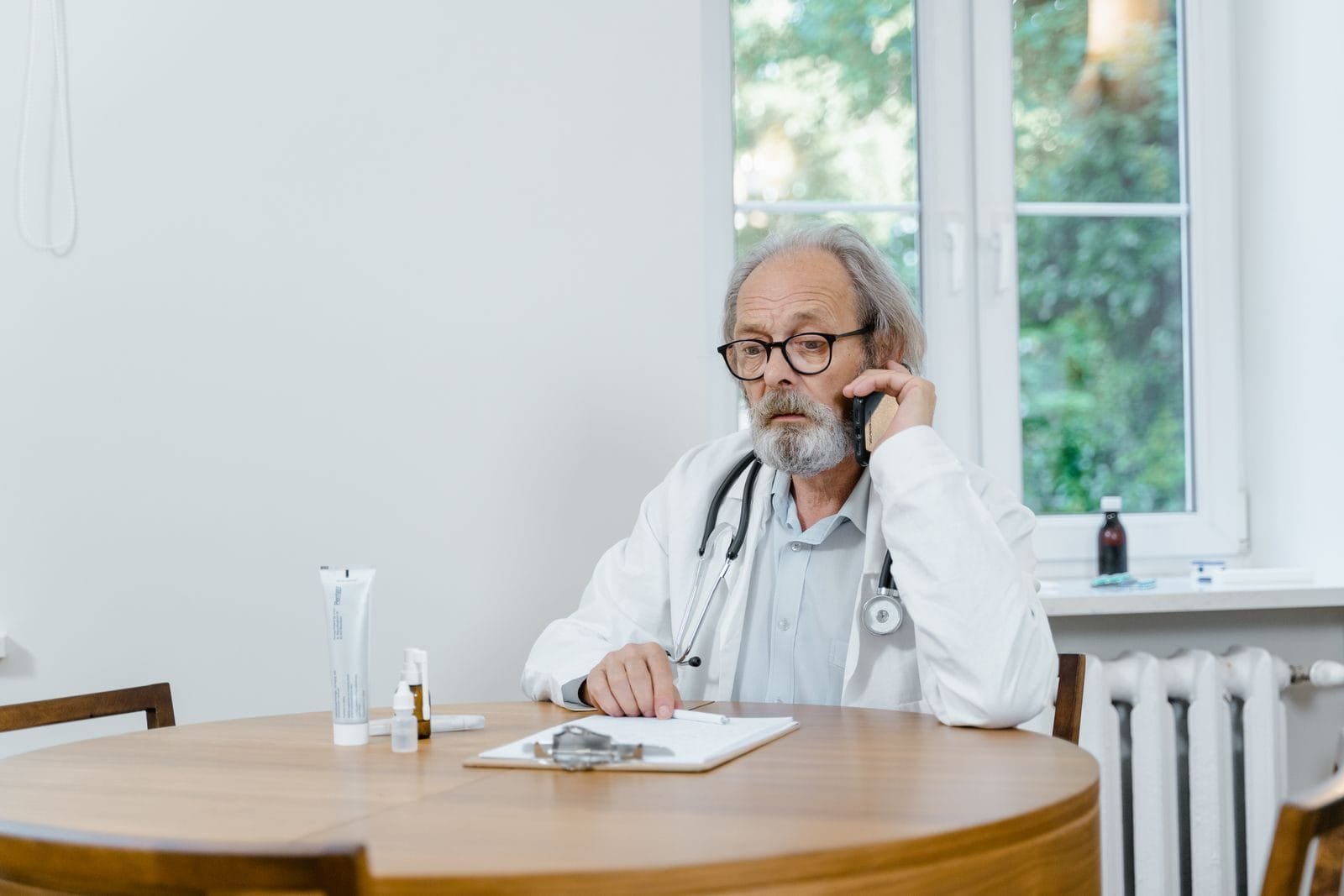Central 135 Volta a Funcionar em Recife (PE) em 2026 1 A senior doctor making a telemedicine call in an office setting, discussing medical cases.