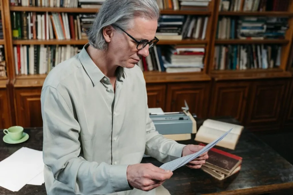 Checklist de documentos para o BPC/LOAS 1 Senior man with gray hair reading documents in a cozy library.