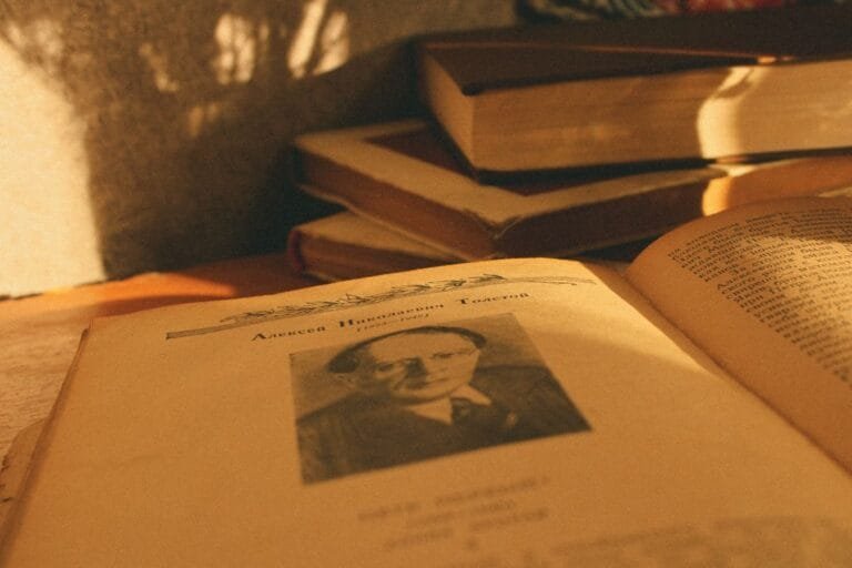 Resultados 6 A stack of vintage books in warm sunlight with an open page displaying a portrait.