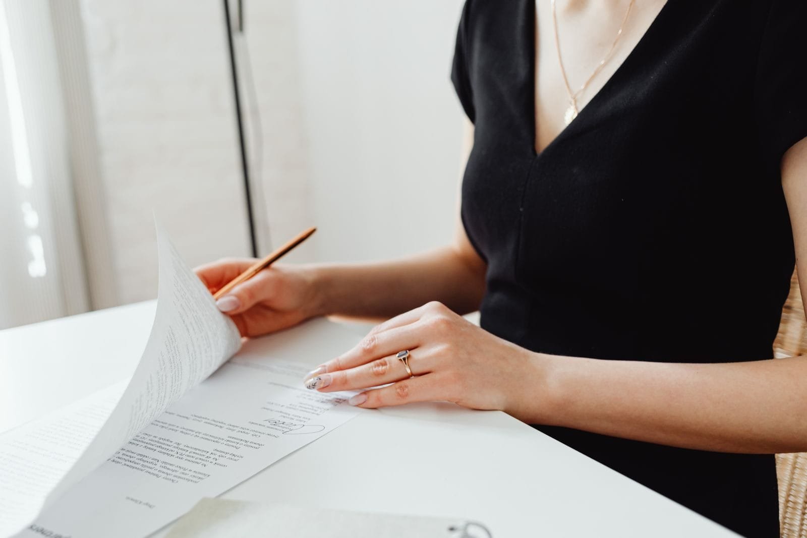 Cláusula Abusiva em Contrato: Como Identificar e Anular 1 Woman with manicured nails examining documents at a desk, emphasizing detail and professionalism.