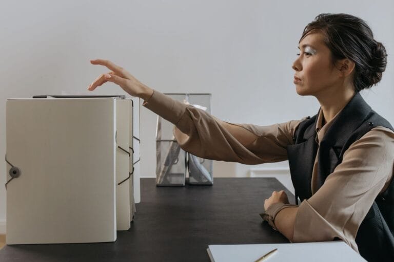 CNIS Errado: Como Corrigir Vínculos no INSS em 2026 2 Asian woman efficiently organizing documents at an office desk.