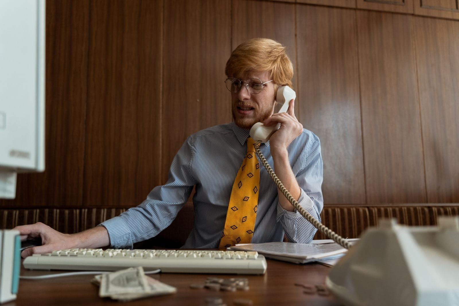 Cobrança indevida e o direito à devolução em dobro do valor pago 1 A man in business attire using a vintage telephone and computer in an office setting.