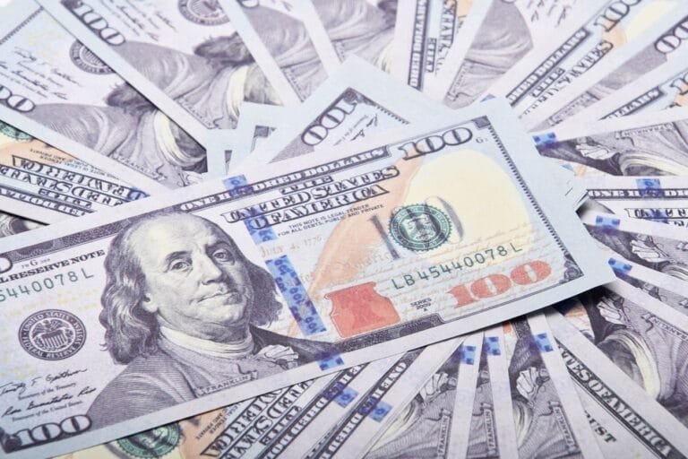 Como podemos ajudar? 8 A stack of hundred dollar bills spread out, symbolizing wealth and financial success.