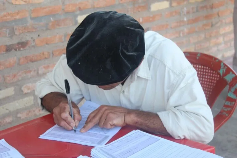 Como funciona o processo administrativo e quais direitos o cidadão tem nele 2 Male adult writing on papers wearing a flat cap, indoors with a brick wall backdrop.